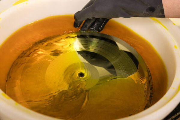 Metal part getting cleaned in chemicals by an employee