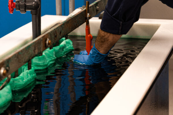 Employee reaching in to plating tank