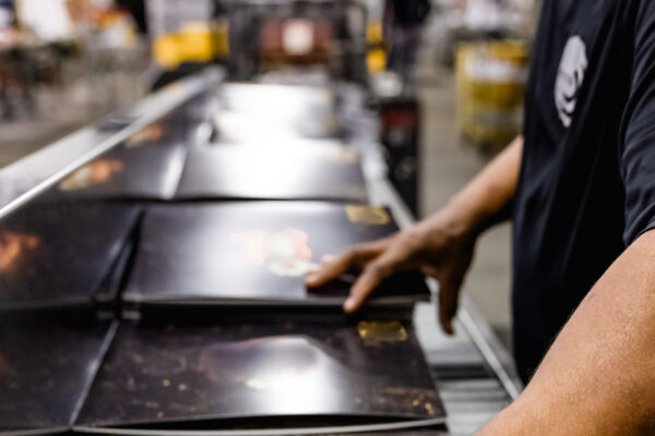 Worker moving vinyl records down the shrink wrap line