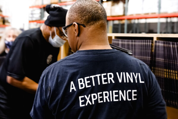 Backside of employee wearing T-shirt that says "A Better Vinyl Experience"