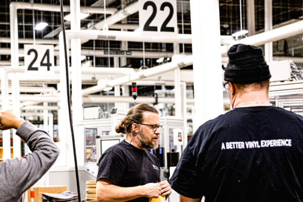 Workers standing beside vinyl record press