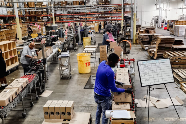 Workers boxing up vinyl record in shipping warehouse
