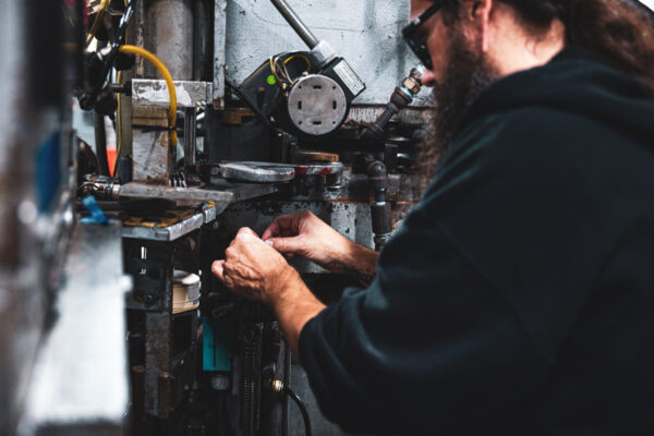 Employee making adjustments to a vinyl record press machine