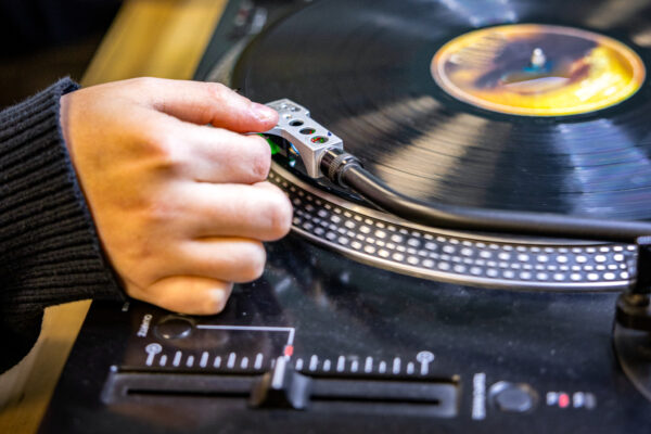 Worker placing turntable needle onto vinyl record