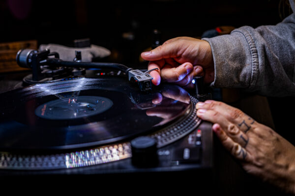 Worker placing turntable needle onto vinyl record