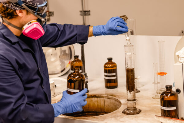 Plating employee mixing chemicals in a beaker